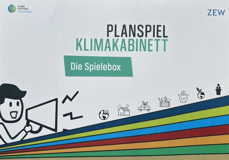 Die Spielbox des Planspiels "Klimakabinett" mit farbigen grafischen Elementen ist zu sehen.